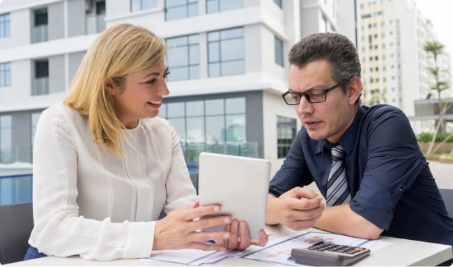 Mujer enseñándole una tablet a un hombre, que la mira concentrado